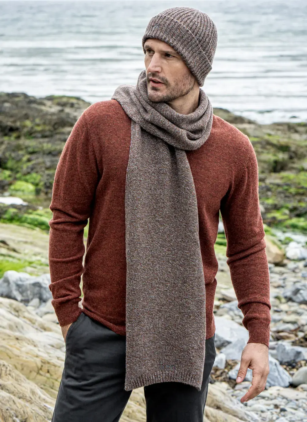 Personalized cashmere wool scarf in hazel brown, made in Ireland, styled with rust sweater and coastal backdrop